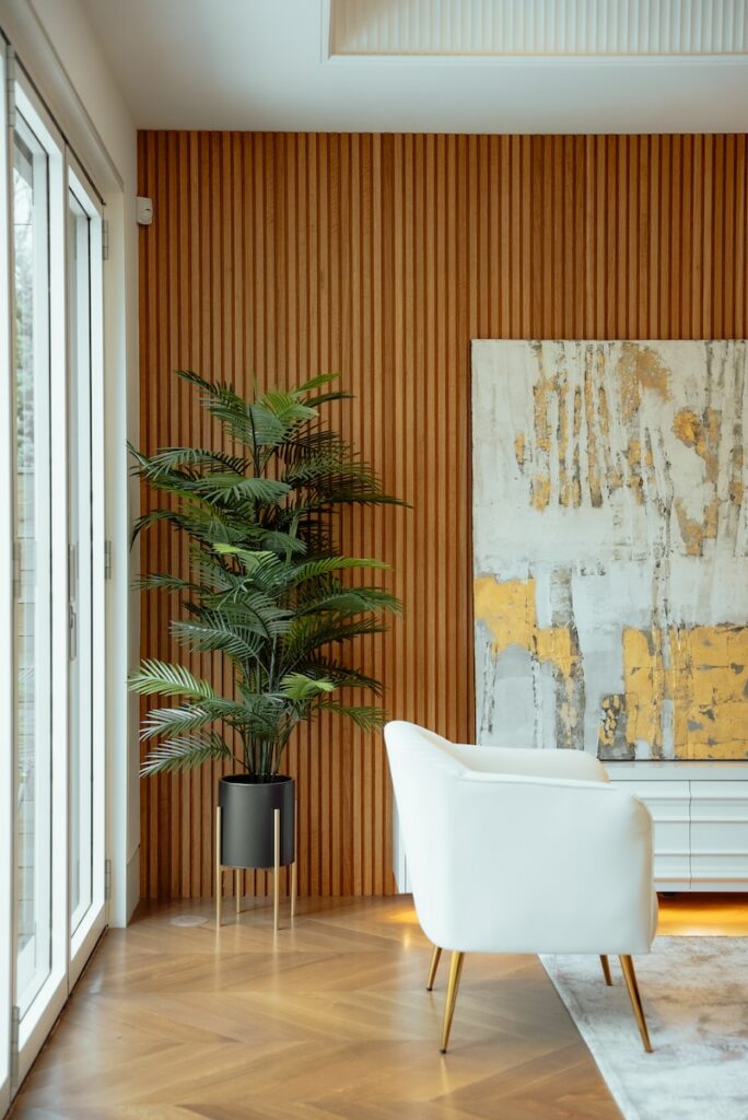 una silla y una planta en una habitación con una pared con una pintura